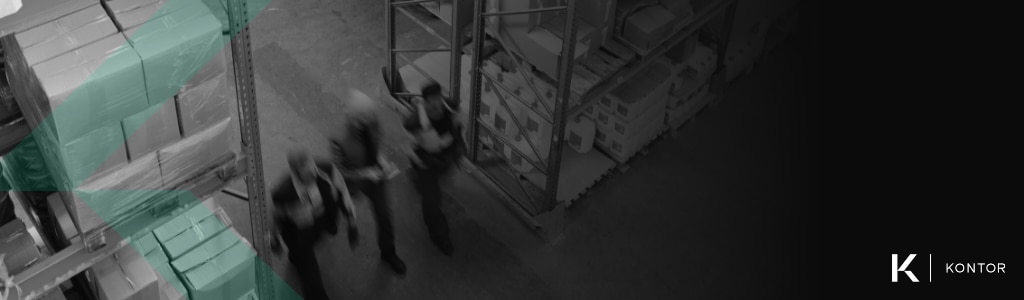 Three men out of focus walking through a warehouse. On the right side is the Kontor logo. On the left side is a green Kontor watermark.