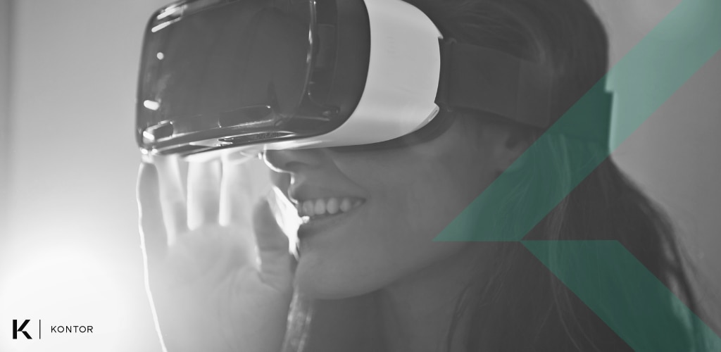 Person with long hair wearing a VR white and black VR headset, smiling. The image is black and white, with a green lines on top if it. The Kontor logo is in the bottom-left corner. 